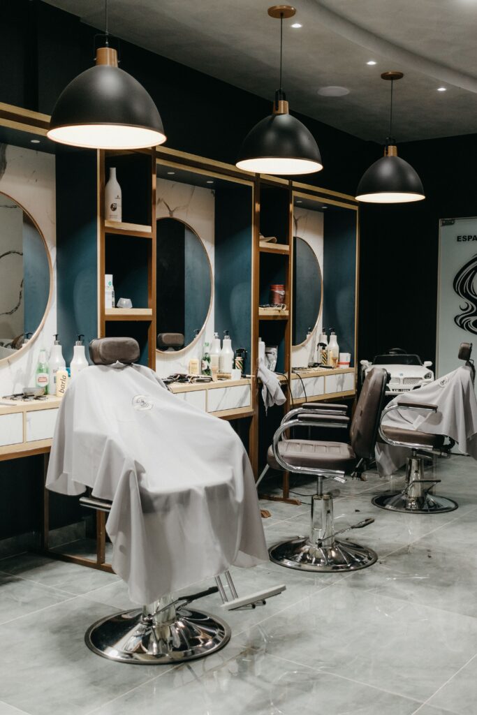Luxurious barbershop interior featuring modern styling chairs, large mirrors, and elegant lighting.