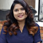Portrait of a smiling woman with curly hair in a salon, capturing a warm and inviting atmosphere.